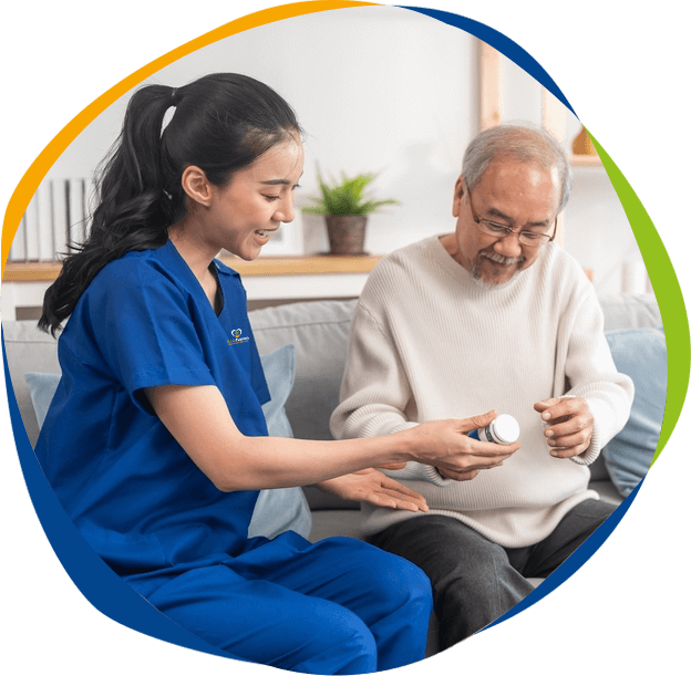 Younger Female Senior Services worker helping an older man with his pills.